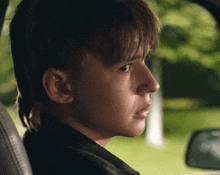 a young boy is sitting in the back seat of a car and looking out the window