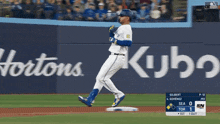 a baseball player runs to first base in front of a kubota ad