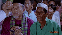 a man in a green shirt is sitting next to another man