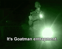a man holding a flashlight in the dark with the words it 's goatman entrapment below him