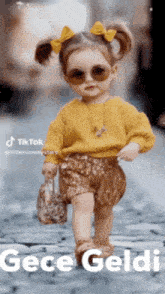 a little girl wearing sunglasses and a yellow sweater holds a purse