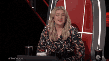 a woman is sitting in a chair with a nbc cup