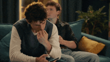 a man sitting on a couch looking at a phone