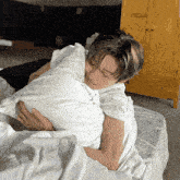 a man laying on a bed holding a pillow that says " i love you "