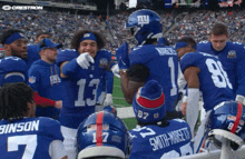 a group of new york giants players huddle on the field