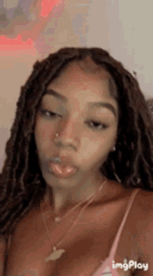 a woman with dreadlocks and a nose ring is wearing a pink tank top .