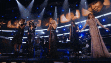 a group of women are singing on a stage