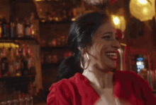 a woman in a red dress is smiling in front of a bar .