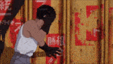 a man is covering his face in front of a wall with chinese writing on it