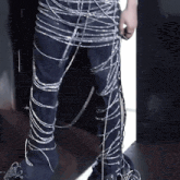 a person 's legs are wrapped in barbed wire and a hand is visible