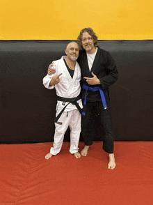 two men are posing for a picture and one has a blue belt with the letter j on it