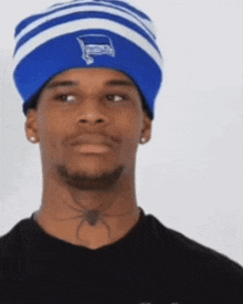 a man wearing a blue and white beanie has a spider on his neck