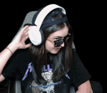 a woman wearing sunglasses and headphones is sitting in a chair .