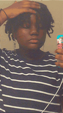 a woman in a striped shirt is taking a picture of herself in the mirror