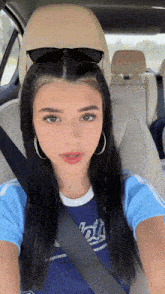 a girl wearing a shirt that says ' hills ' on it sits in a car