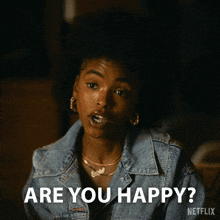 a woman in a denim jacket says " are you happy " in white letters