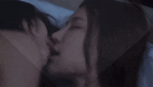 a man and a woman kissing on a bed with their eyes closed