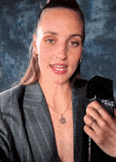 a woman in a striped suit is holding a bottle of perfume that says this game is who