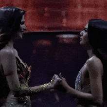 two women holding hands in front of a screen