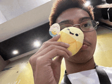 a man wearing glasses is holding a stuffed animal with a sticker that says " banana " on it