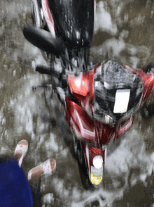 a red motorcycle with a license plate that says ' a ' on it is in a puddle of water