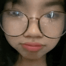 a close up of a woman wearing glasses and making a face .