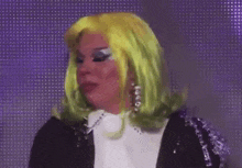 a drag queen wearing a green wig and earrings is making a funny face .