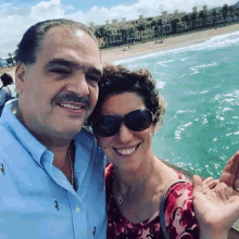 a man and a woman are posing for a picture on a beach