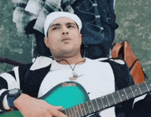 a man laying down playing a guitar with a watch on
