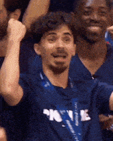 a man wearing a blue shirt that says ' home ' on it holds his fist in the air