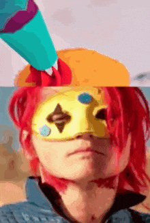 a person with red hair is wearing a yellow mask and a blue hat .