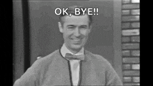 a man in a bow tie and sweater is smiling and saying `` ok , bye '' .