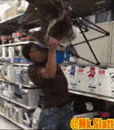 a man holds a chair upside down in a store with a yellow sticker that says @ mk.slatt