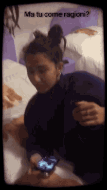 a woman laying on a bed looking at her phone with the words ma tu come ragione