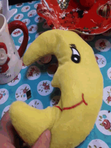 a person is holding a yellow stuffed animal that looks like a worm