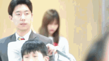 a man in a suit and tie is cutting a boy 's hair .
