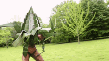 a person in a green origami costume is standing in a grassy field