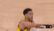 a man in a yellow and black basketball uniform holds his neck