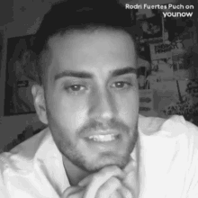 a black and white photo of a man with a beard and a white shirt .
