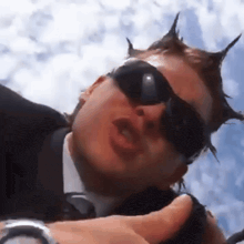 a man wearing sunglasses and a suit with spikes on his head
