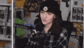 a girl wearing a black hat with a flower on it is talking into a microphone