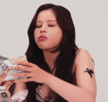 a woman with a tattoo on her arm is eating food .