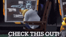 a cartoon character is sitting in a chair with the words check this out written on the screen behind him