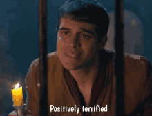 a man behind bars holding a candle with the words positively terrified above him