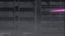a robot with red eyes is standing in front of a building with purple lights coming out of it .