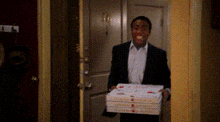 a man in a suit is holding a stack of pizza boxes in his hand .