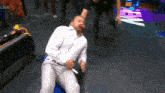 a man in a white shirt is laying on the floor with blood on his face while a referee stands behind him .