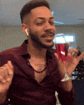 a man in a maroon shirt holds a glass of red wine