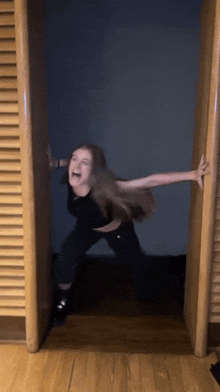 a woman is standing in a doorway with her arms outstretched and screaming