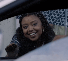a woman is smiling while holding an umbrella in a car window .